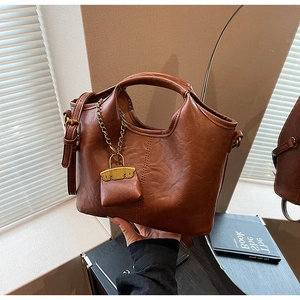 Détail du sac seau en cuir PU caramel avec poignée et mini pochette décorative