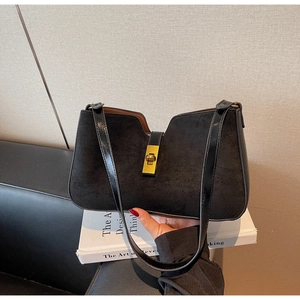 Gros plan du fermoir rotatif doré sur un sac à main noir en daim mat et cuir lisse