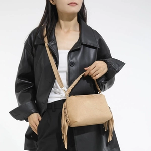 Close-up of camel suede bag featuring fringed edges and a stylish woven top handle
