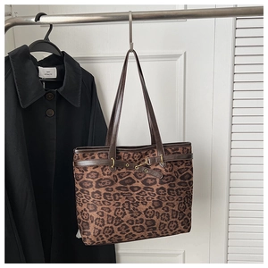 Détail d'un sac cabas léopard avec anses en cuir marron et boucle en métal doré