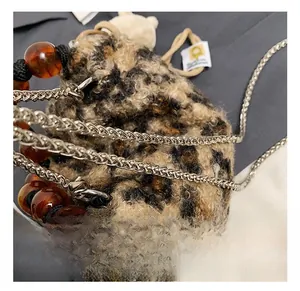 Detail of leopard print plush bag featuring amber beads and a silver chain strap