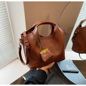 Détail du sac seau en cuir PU marron avec mini pochette et accents de chaîne dorée