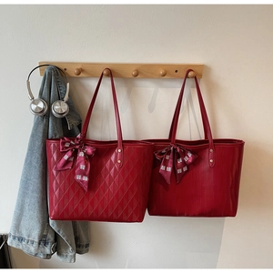 Detail view of red leather tote bags with quilted texture and silk scarf decoration