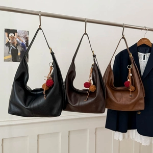 Three minimalist large hobo bags in black, dark coffee, and tan with pompom charms