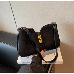 Détail du sac seau en cuir noir mat avec fermoir métallique doré et finitions brillantes