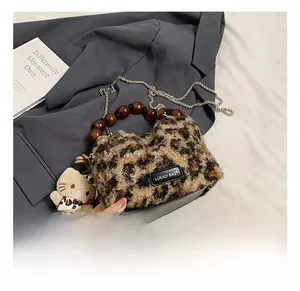 Leopard print plush handbag featuring round bead handles and a cat charm detail