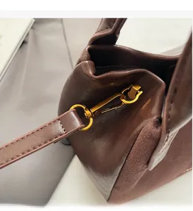 Nahaufnahme goldener Metallhaken und D-Ringe an dunkelbrauner Vintage-Wildledertasche