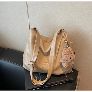 Detail of beige faux leather tote with Banat logo and a brown plush bear charm