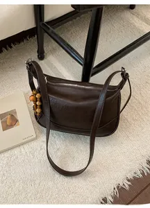 Dettaglio borsa a mezzaluna marrone scuro con perline in legno e zip in metallo argento
