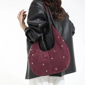 Dettaglio ravvicinato della borsa hobo in pelle scamosciata bordeaux con borchie dorate