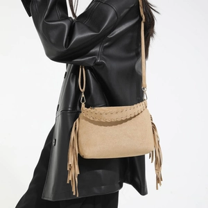 Close-up of matte brown suede crossbody bag with fringe and woven stitching details