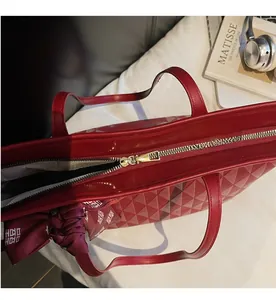 Detail view of the smooth golden metal zipper and quilted texture on the burgundy tote bag