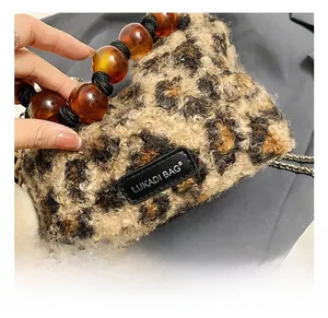 Detail of leopard faux fur tote featuring amber resin bead handle and metal chain strap