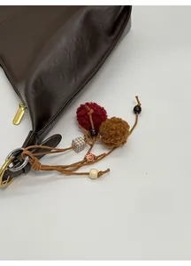 Detailed close-up of dark brown leather bag with boho charms and vintage wooden beads