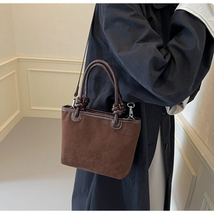 Close-up of brown suede bucket bag featuring embossed floral patterns and twisted handles