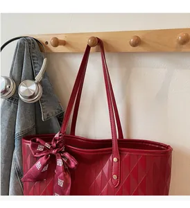 Detail of red quilted faux leather tote bag with festive silk scarf and classic pattern