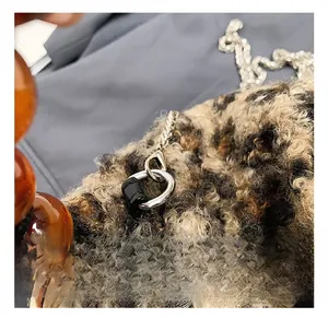 Close-up of leopard print plush bag with silver metal hooks and brown beaded handles