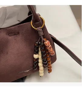 Detailansicht der dunkelbraunen matten Ledertasche mit farbigem Holzperlen-Anhänger