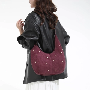 Dettaglio della borsa hobo in pelle scamosciata bordeaux con borchie dorate sulla modella