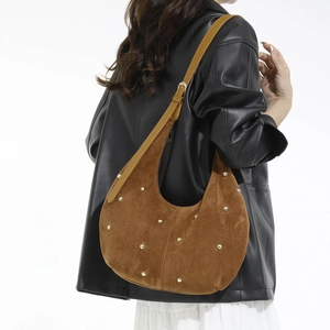 Borsa hobo in camoscio marrone con borchie dorate indossata a spalla da una modella