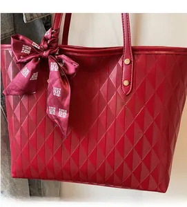 Detail of red tote bag with quilted texture, gold studs, and festive red ribbon bow