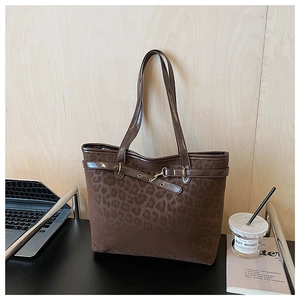 Détail de la texture suédée léopard et de la bandoulière en cuir verni marron du sac cabas