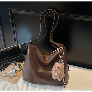 Macro detail of dark brown hobo bag with wrinkled PU leather texture and dog charm