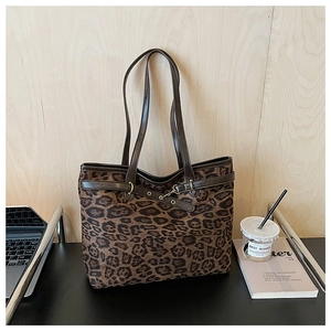 Détail d'un sac cabas léopard avec garniture en cuir brun sur un bureau avec café