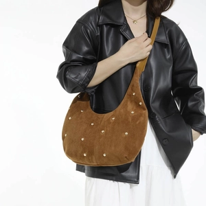 Dettaglio borsa hobo in camoscio marrone con borchie dorate e silhouette a mezzaluna