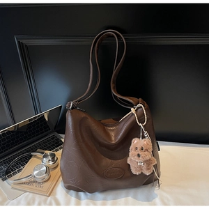 Detail of dark brown faux leather bucket bag with retro texture and plush dog pendant