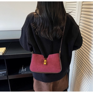 Vue détaillée du daim bordeaux et du fermoir doré métallique sur le sac seau à bandoulière