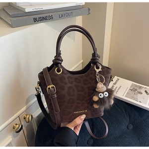 Detailed close-up of leopard print suede handbag with gold logo and monster charm