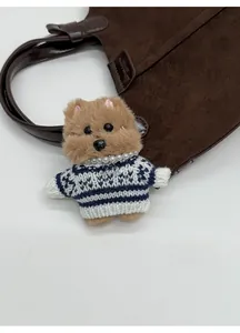 Close-up of light brown plush dog charm with striped sweater and pearl necklace detail