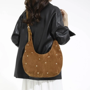 Borsa hobo in pelle scamosciata marrone con borchie dorate e tracolla indossata
