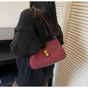 Détail du sac à bandoulière en daim bordeaux avec un fermoir rotatif en métal doré vintage