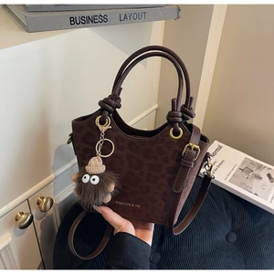 Detailed close-up of dark brown leopard print bucket bag with golden logo and plush charm