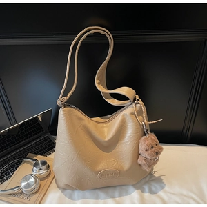 Detail of beige bucket bag with natural wrinkled texture and cute plush puppy charm