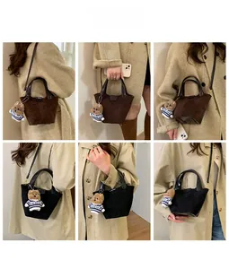 Detail view of suede bucket bag with leather handles and cute plush bear charm