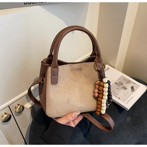 Detailsicht der braun-beigen Patchwork-Lederbeuteltasche mit Holzperlenanhänger