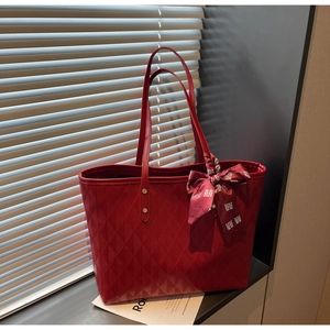 Detail of red quilted tote bag with festive silk scarf featuring traditional knots