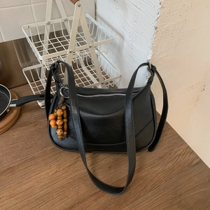 Detail of black faux leather commuter bag with silver zipper and wooden bead charm