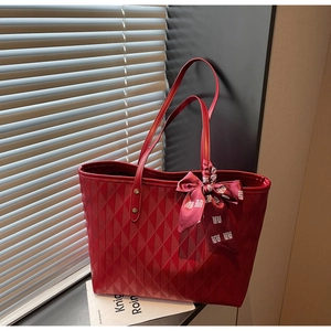 Detail of red quilted tote bag featuring a decorative silk scarf with traditional pattern