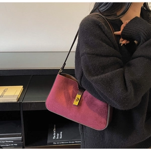 Détail de la texture en daim bordeaux et boucle dorée sur un sac à bandoulière rétro
