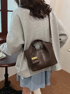Sac à main seau minimaliste marron foncé en cuir avec bandoulière réglable et breloque dorée