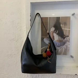 Detailed view of black leather Hobo shoulder bag with colorful ethnic tassel charms