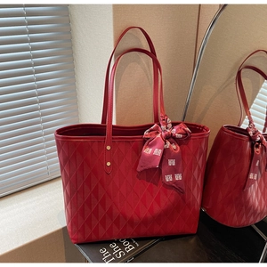 Macro detail of red tote bag with rhombus texture and festive silk scarf in soft natural light