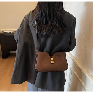 Gros plan du sac seau en daim marron moka avec fermoir rotatif en métal doré vintage