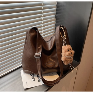 Close-up of vintage brown pleated leather bucket bag with a cute plush bear pendant