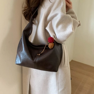 Detail of dark brown vintage faux leather shoulder bag with plush pompom charms decoration