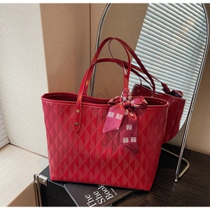Detail of red quilted tote bag featuring a decorative silk scarf with traditional pattern